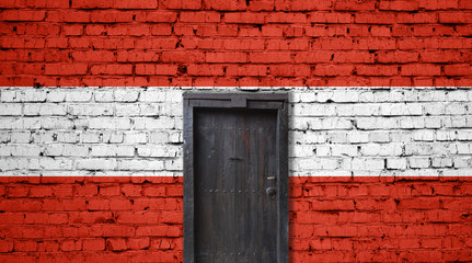 Austria flag on brick wall. Closed door in a wall