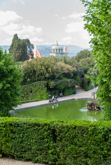 Fototapeta premium Florence cathedral domes emerging above garden trees with green pond in the center