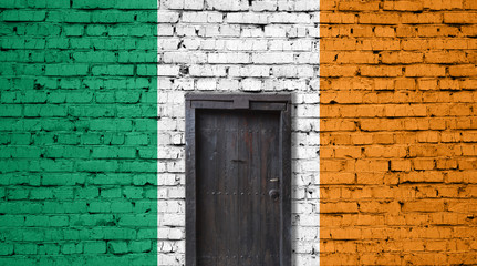 Ireland flag on brick wall. Closed door in a wall