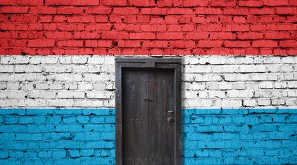 Luxembourg flag on brick wall. Closed door in a wall