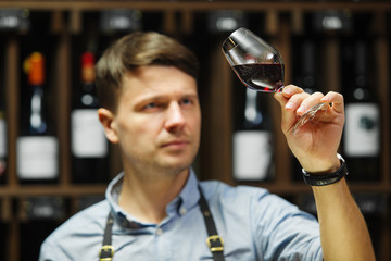 Bokal of red wine on background, male sommelier appreciating drink