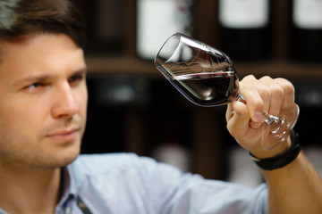 Bokal of red wine on background, male sommelier appreciating drink