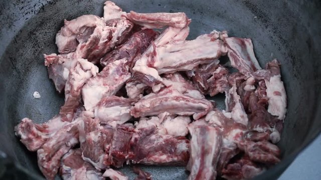 Cooking on the open fire. Raw lamb ribs prepared for cooking lying in a cast-iron cauldron. HD