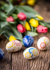 Fototapeta na wymiar Easter. Hand made easter eggs and spring tulips on old wooden table.