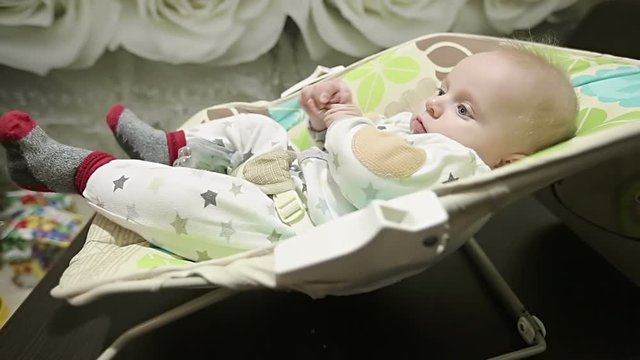 Side view. Baby shaking legs in the nursery rocking chair.