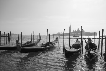 Gondolas in Venice, Italy tied to the pillars with San Giorgio church in the background, black and white