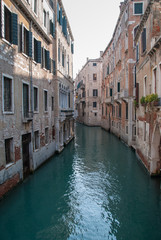 Fototapeta na wymiar Narrow water canal, ancient buildings with rustic brick facades, Venice, Italy