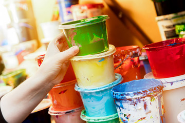 Artist reaching for a liquid paint container.