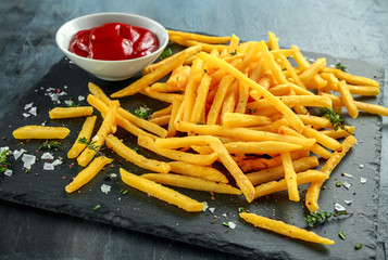 French fries with sea salt, cracked pepper and ketchup on stine board