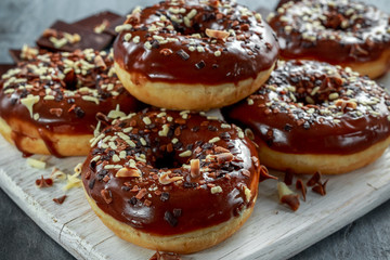 Obraz na płótnie Canvas donut rings with white and dark chocolate chippings and icing served on board