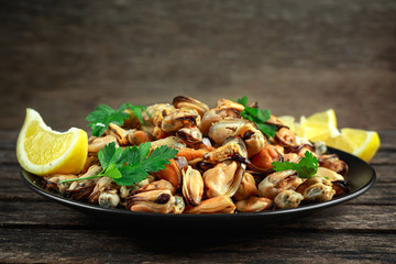 Seafood. Steamed Musseles appetizer with sprinkle of parsley and lemon juce served on black plate.