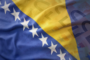 colorful waving national flag of bosnia and herzegovina on a euro money banknotes background.