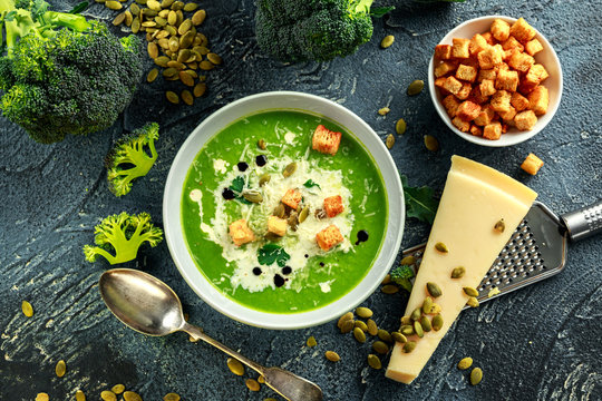 Dietary Broccoli smooth cream soup with sprinkle of sunflower seeds, parsley leaves and croutons on stone table.