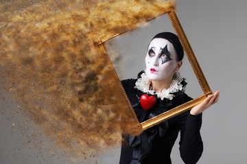 Woman in disguise harlequin in the picture frame. Photo manipulation