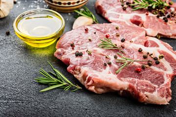  Raw pork steaks  with oil and spices on dark bakground.