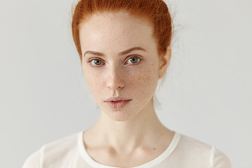 Close up studio shot of beautiful charming redhead European model with healthy freckled skin...