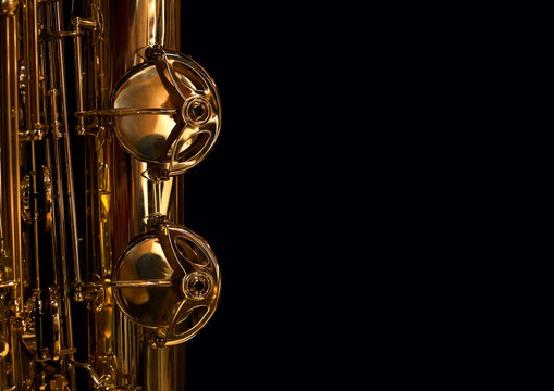 Fragment of saxophone valves in gold tones on a black background