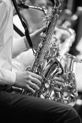 Obraz premium Saxophone in the hands of a musician in an orchestra in black and white