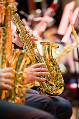 Saxophone in the hands of a musician in an orchestra closeup 