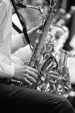 Saxophone in the hands of a musician in an orchestra in black and white