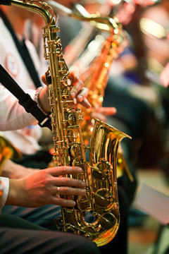 Saxophone in the hands of a musician in an orchestra closeup