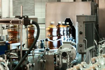 Plastic bottles filled with beer on the conveyor of the filling machine.
