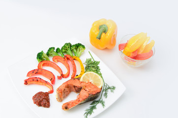 Grilled red fish with sauce, broccoli, parsley and dill  on a white plate