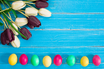Easter eggs and tulips on blue wooden planks