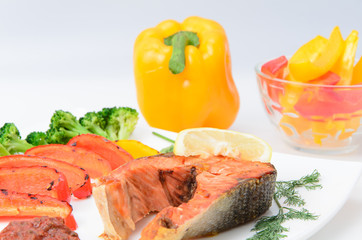 Grilled red fish with sauce, broccoli, parsley and dill  on a white plate