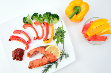 Grilled red fish with sauce, broccoli, parsley and dill  on a white plate