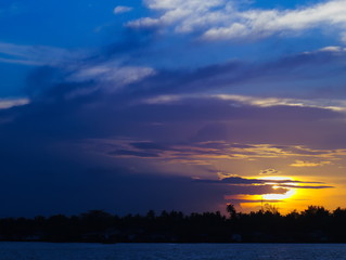 sunset with cloudy sky with trees and river