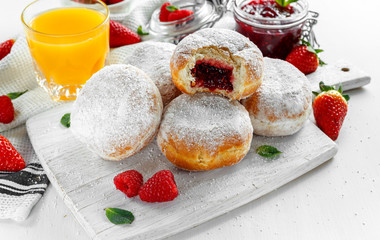 Fresh tasty donuts with ripe berries and raspberries jam on white wooden board.