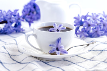 Obraz na płótnie Canvas Cup of black coffee, and purpule hyacinth flowers on napkin