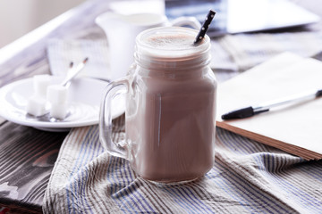 Glass jar of coffee with cream Tablet Sunglasses and sugar on background Wooden table