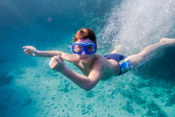 Boy in swimming mask deep dive in Red sea near coral reef