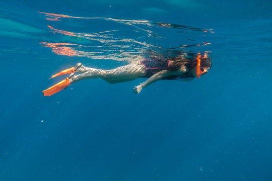 Girl in swimming mask and flippers dive in Red sea