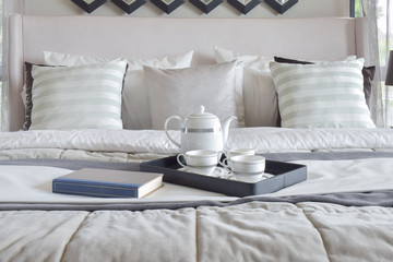 Decorative tray with book and tea set on the bed in modern bedroom