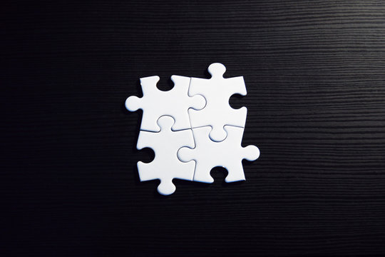 Vier zusammenh&auml;ngende Puzzleteile auf schwarzem Grund