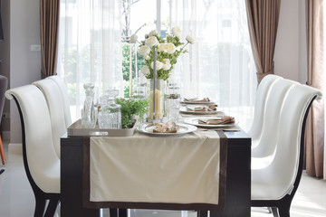 dining wooden table and comfortable chairs in modern home with elegant table setting