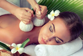 Body care. Spa body massage treatment with hot  herbal ball for deep relaxation . Woman having massage in the spa salon 