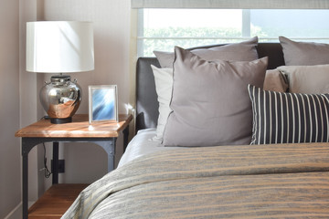 stylish bedroom interior design with striped pillows on bed and decorative table lamp.