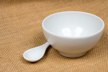 empty white bowl with spoon over sackcloth