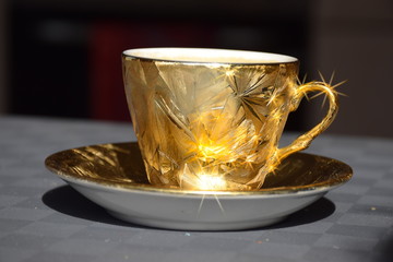 Goldene Tasse mit Kaffee und Kaffeebohnen mit Sterneffekt