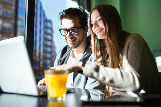 Beautiful young couple working with laptop in the coffee.
