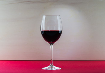 Polished still life glass of wine with nice light effect in red and beige background