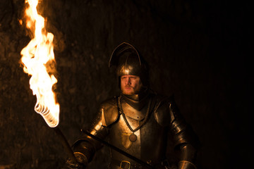 Knight with a torch and sword at night on a wall background