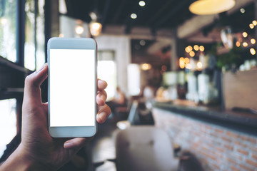 Mockup image of a hand holding white mobile phone with blank white screen in vintage cafe