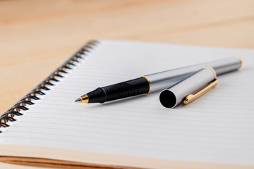 pen and book on wood background