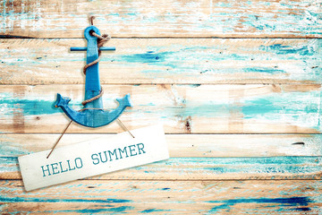 Vintage Hello summer sign hanging with anchor on old wooden blue paint background. vintage wood...