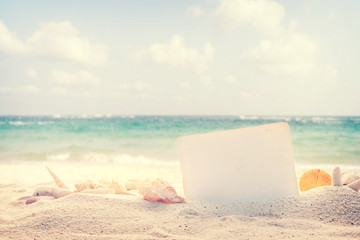 Vintage summer beach background with sand, shells and empty paper for your message design. Concept of summertime relax on beach.